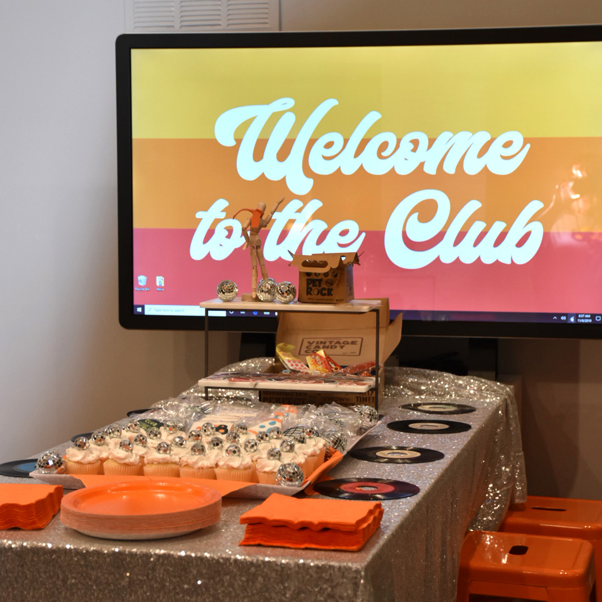 Welcome to the Club sign and a table setup with treats.