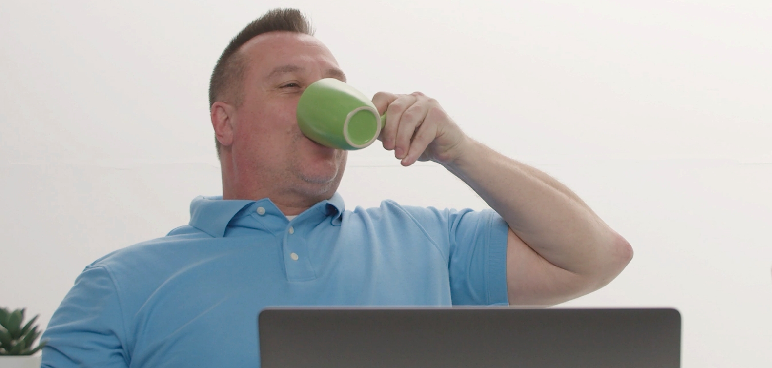 Closeup of Scott drinking coffee from a green coffee cup.