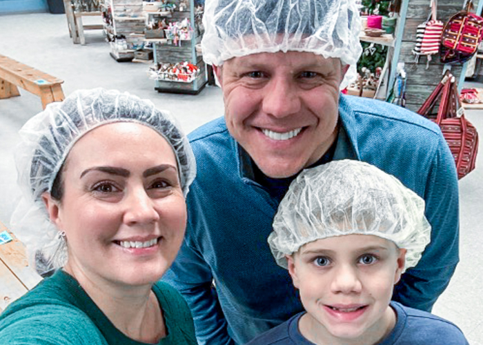 img-sn-community3-700-1 Family members wearing hairnets smiling together at a community service event indoors.